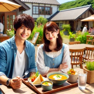 アウトドアヴィレッジのカフェテラスでランチを楽しむ日本人の美人女性とイケメン青年。テーブルには地元の新鮮な食材を使ったカレーやサンドイッチが並ぶ。
