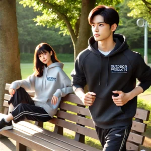 若い男女がアウトドアプロダクツのパーカーを着て公園でリラックスしている様子。