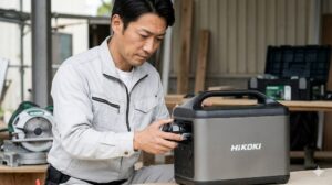 建設現場の休憩所で、HiKOKIのポータブル電源のバッテリーを交換する日本人作業員。プロ仕様の利便性。